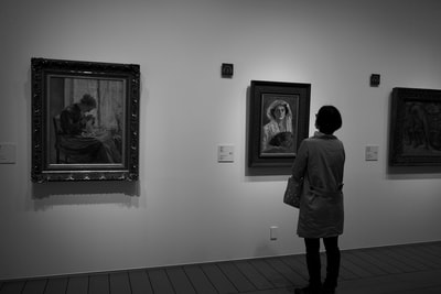 A man in a gray coat stand next to the painting
